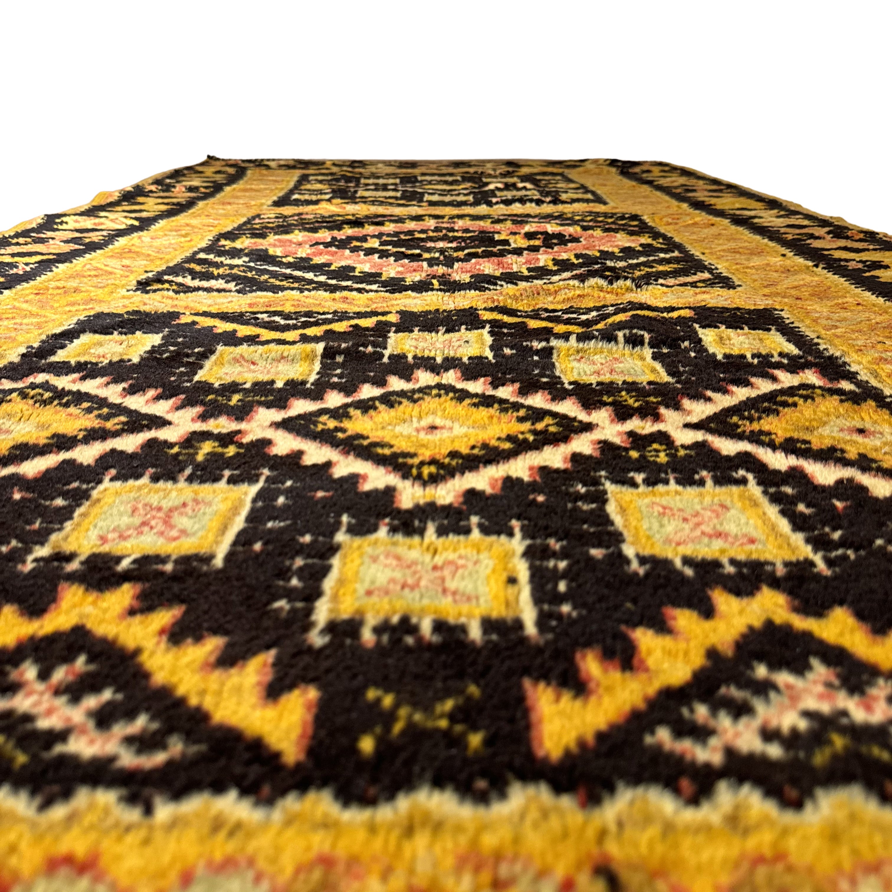 Close-up of a patterned rug with black, yellow, and pink colors on a white background.