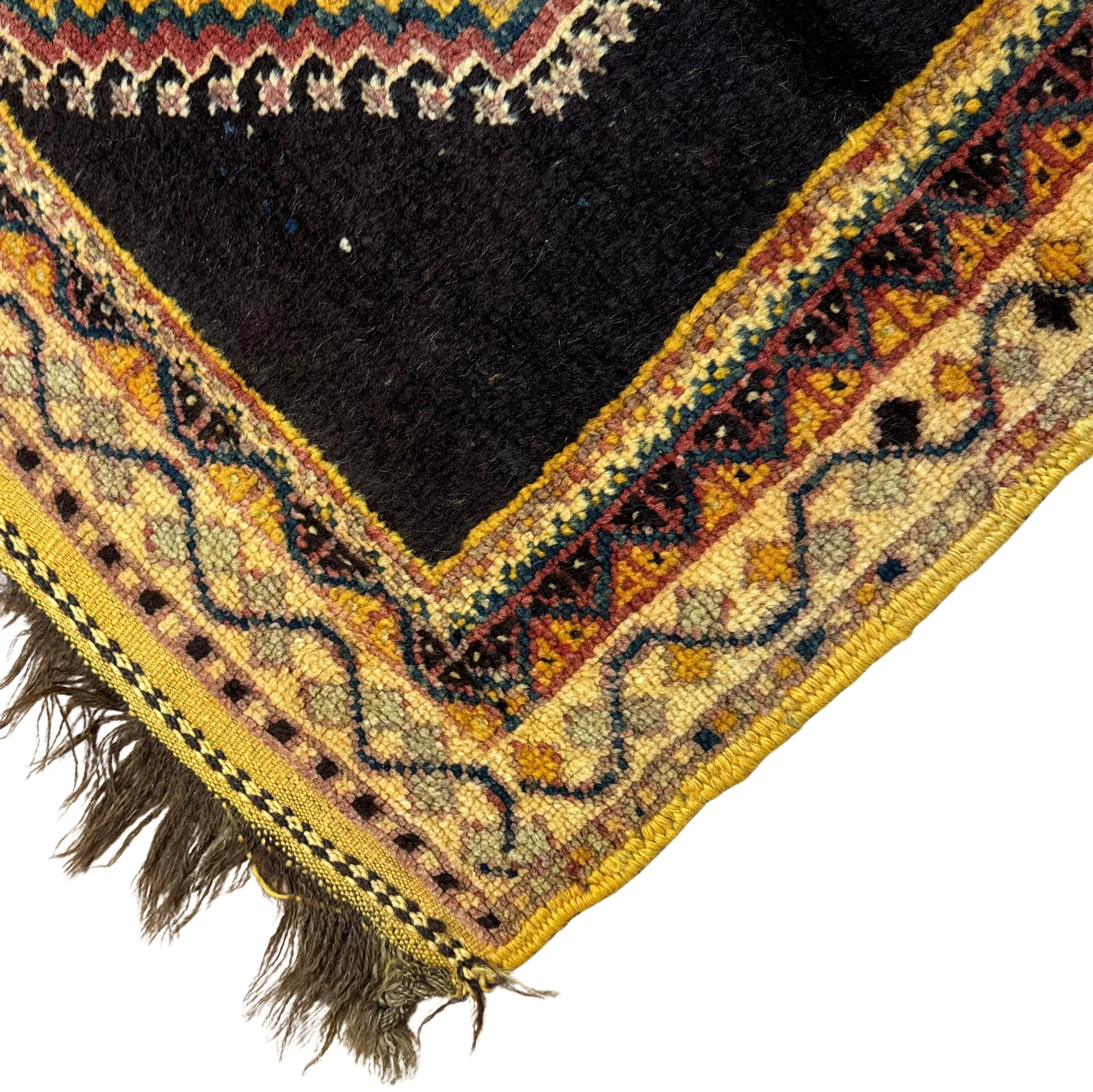 Close-up of a patterned rug corner with intricate designs and fringes.