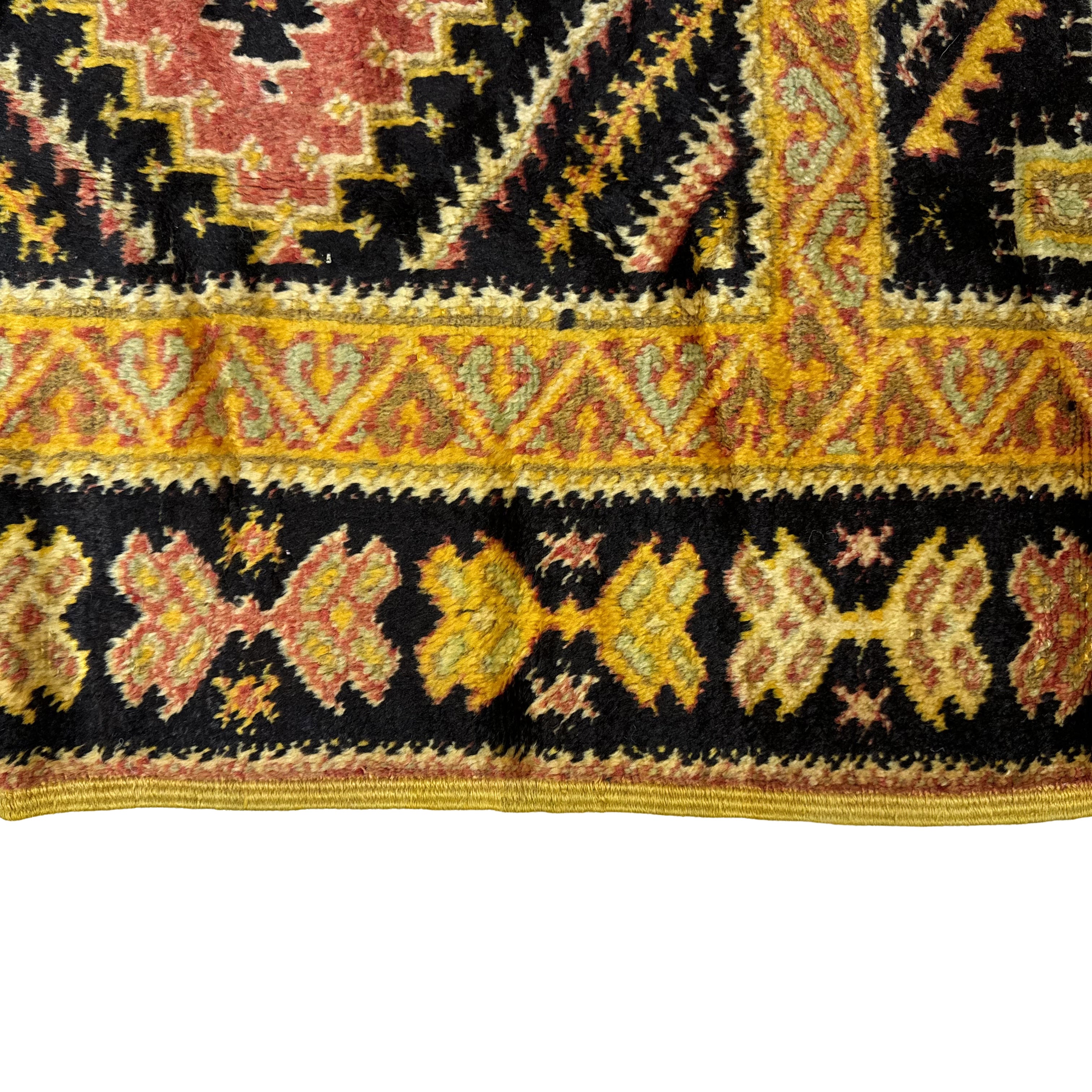 Close-up of a patterned fabric with yellow, red, and black colors on a white background.